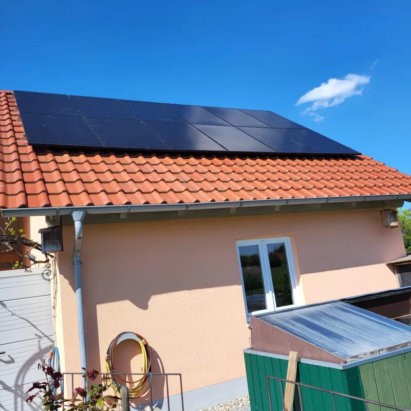 Schwarze Solarmodule auf dem roten Ziegeldach eines Wohnhauses