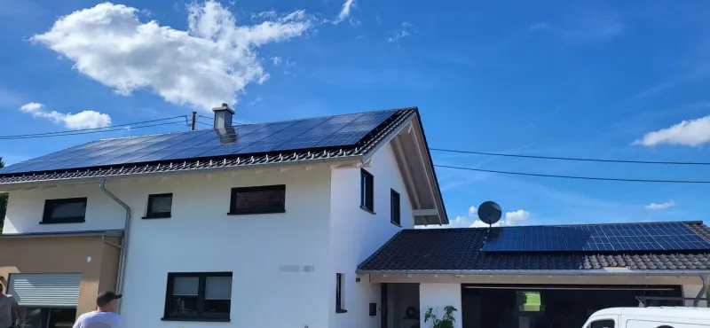 Einfamilienhaus mit Solarmodulen auf dem Satteldach und auf dem Dach der Doppelgarage
